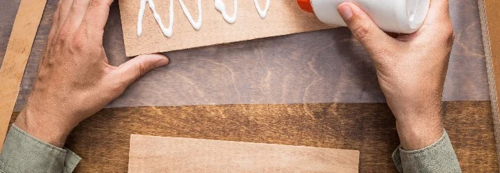 Person trägt Leim auf Holz auf